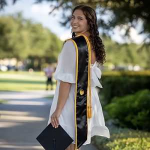 Rhen Myers looks back at the camera and smiles, with a graduation stole perched on her shoulder.