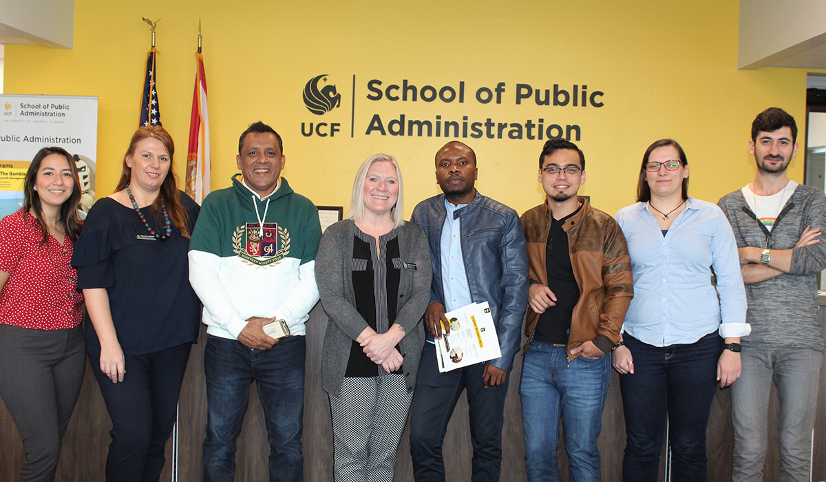 students and faculty pose in front of School of Public Administration