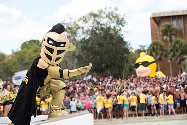 UCF Knightro with crowd of students at a campus event at the reflection pond