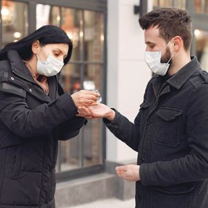 masked people sharing hand sanitizer