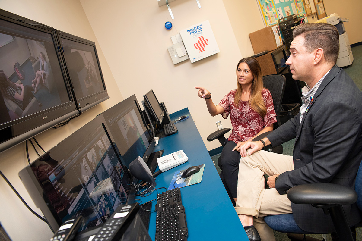 John Super and UCF doctoral student observing counseling students-in-training on computer screens