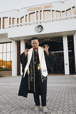 Carlos Aleman poses outside Millican Hall in his graduation gown.