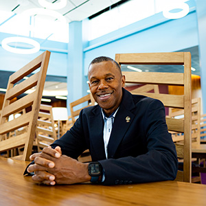 Lee Ross, UCF professor of criminal justice, sits smiling at a table in the library.