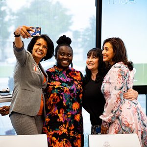 Four graduates of the capacity-building workshop series' latest cohort smile as they take a selfie together.