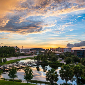 A view of UCF's campus, facing the Fairwinds Alumni Center and Additional Financial Arena, at sunset.