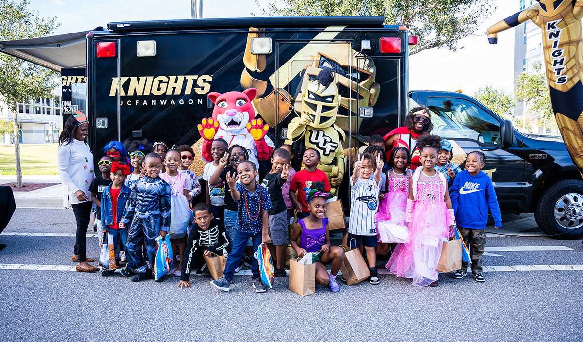 OCPS ACE students pose with the UCF Fan Wagon and Knightro during the Book Character Parade