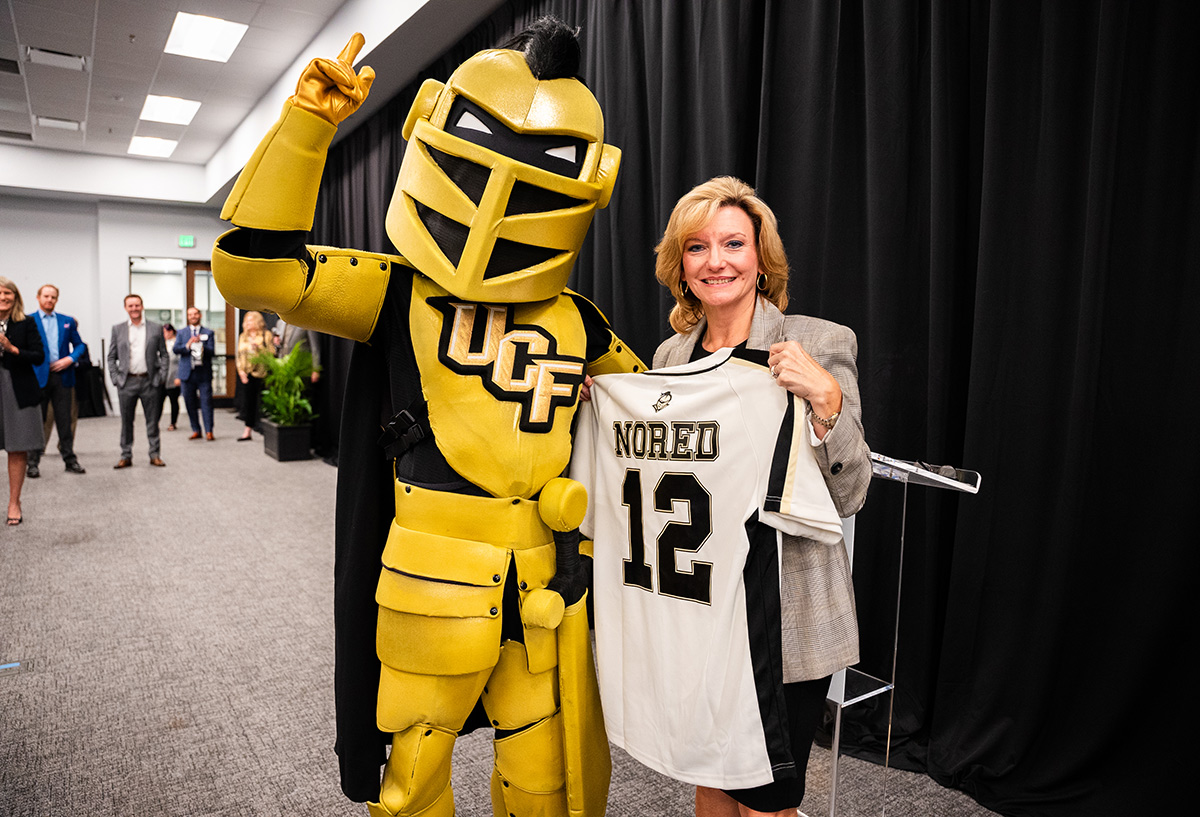 Lisa Nored holding custom jersey with UCF mascot, Knightro