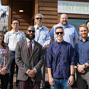 The REACH team stands in front of a "tiny green home" the mobile hubs were inspired by