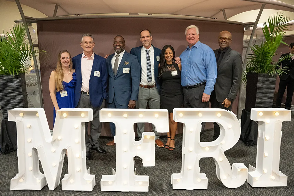 Past and present MFRI and college leaders in front of MFRI marquee letters