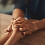 Hands holding eachother on table