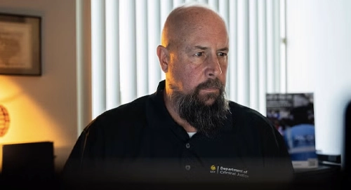 Cory Watkins sitting at desk focused on computer screen