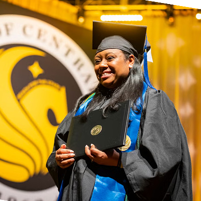 UCF graduate walking at graduation with diploma in hand
