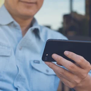 A seated man holds a phone to make a video call
