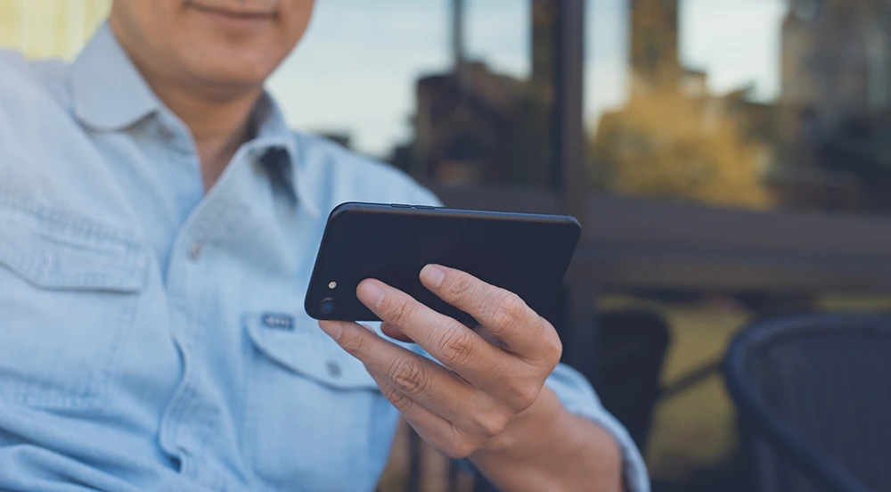 A seated man holds a phone to make a video call