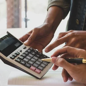 Two sets of hands working with a notebook and calculator